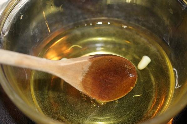 huile de noix de coco et cire d'abeille fondus mélangés avec une cuillère en bois