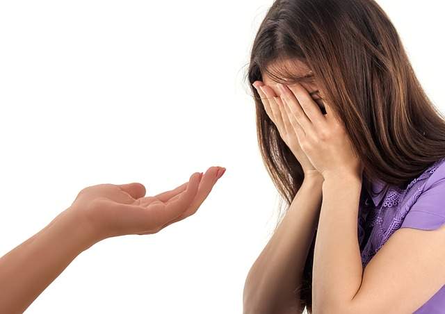 fille qui se couvre le visage avec les mains et main tendue en aide
