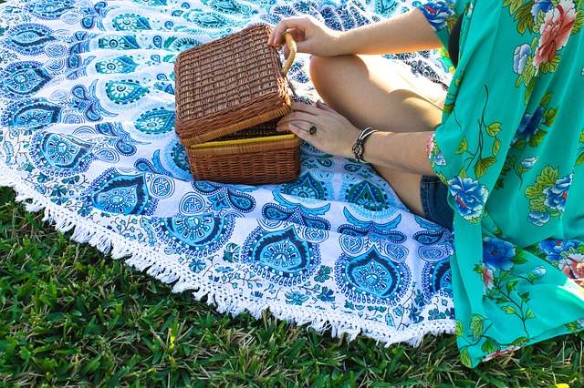 femme assise sur une couverture avec un panier de pique-nique