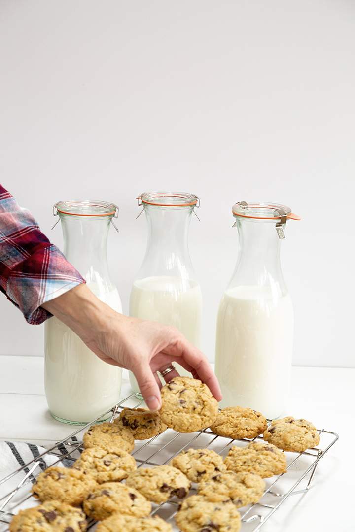 cookies prêts sur un plateau de refroidissement et 3 bouteilles de lait