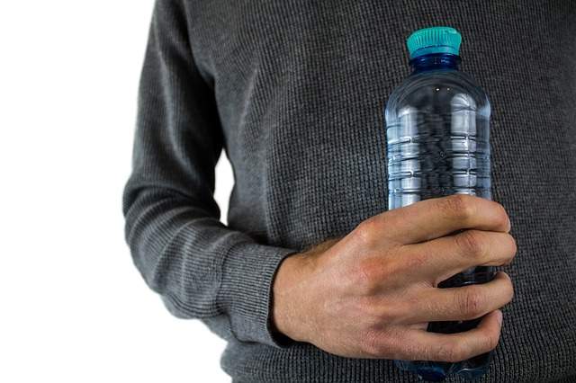 main d'homme tenant une bouteille d'eau