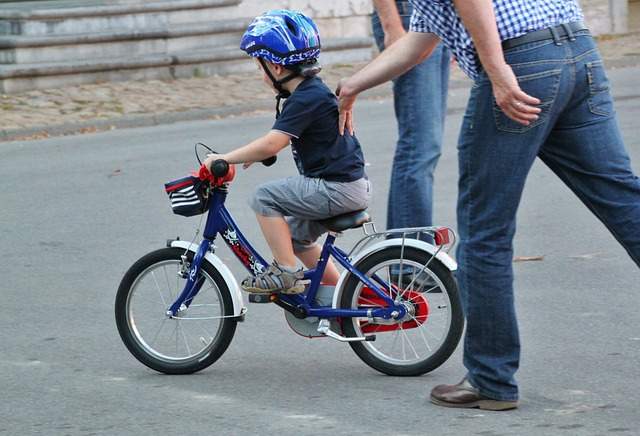 enfant avec son père qui lui apprend à monter à vélo