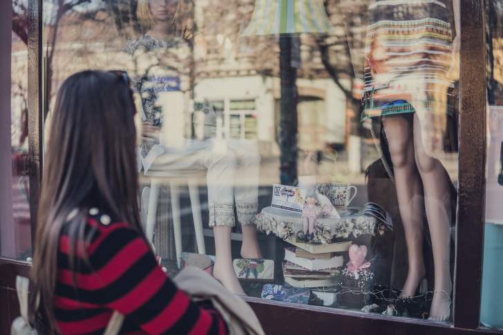 fille devant une vitrine de magasin de vêtements