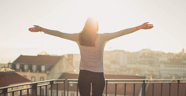 Liberté sérénité femme sur un balcon avec les bras ouverts