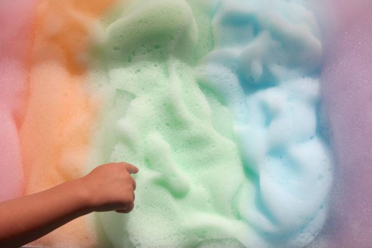 main touchant la mousse multicolore jeu sensoriel