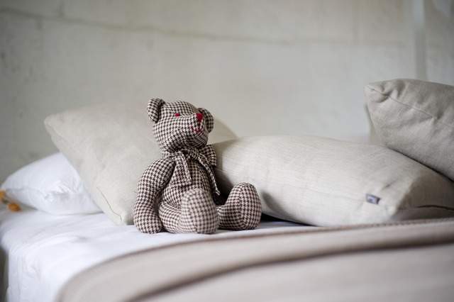 ours en peluche en tissu à carreaux sur un lit avec des coussins
