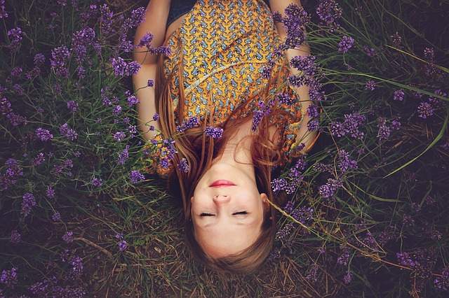 femme qui se détend dans les fleurs en fermant les yeux