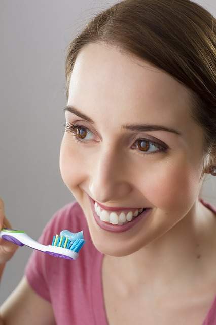 femme souriante qui s'apprête à se brosser ses dents blanches sans tartre dentaire