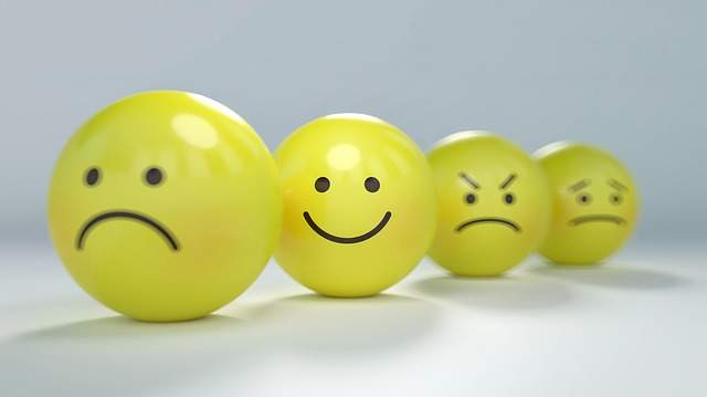 Emoji souriant et content au milieu d'autres emojis tristes