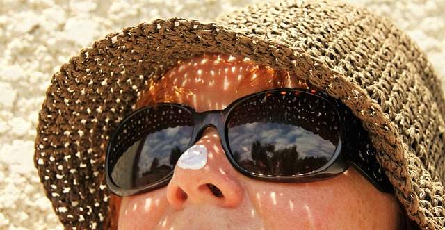 femme avec un chapeau des lunettes de soleil et une crème anti-uv 