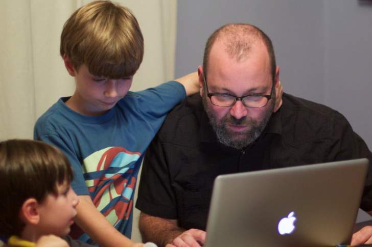 papa qui apprend à ses deux enfants à utiliser un ordinateur