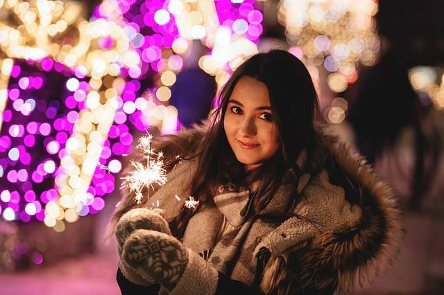 fille en hiver pendant les fêtes de fin d'année tenant un cierge magique