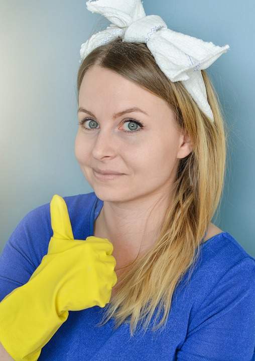 femme souriante avec le pouce vers le haut portant des gants de ménage