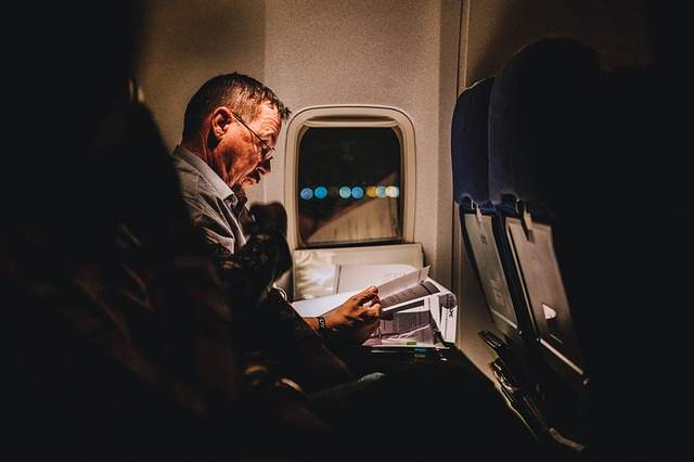 homme entrain de lire assis dans un avion