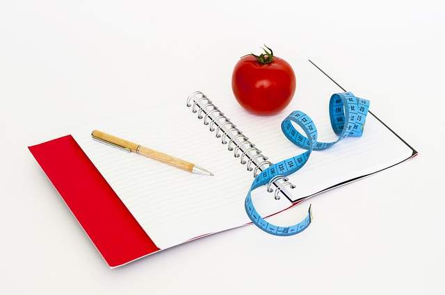 carnet de notes avec un mètre ruban un stylo et une tomate