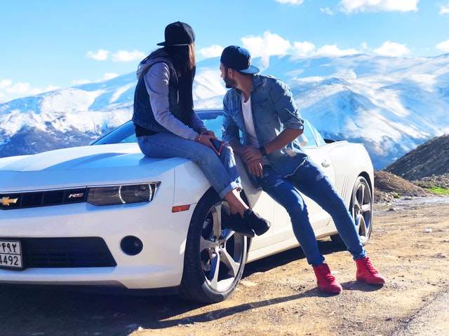couple sur une montagne avec leur voiture de luxe blanche