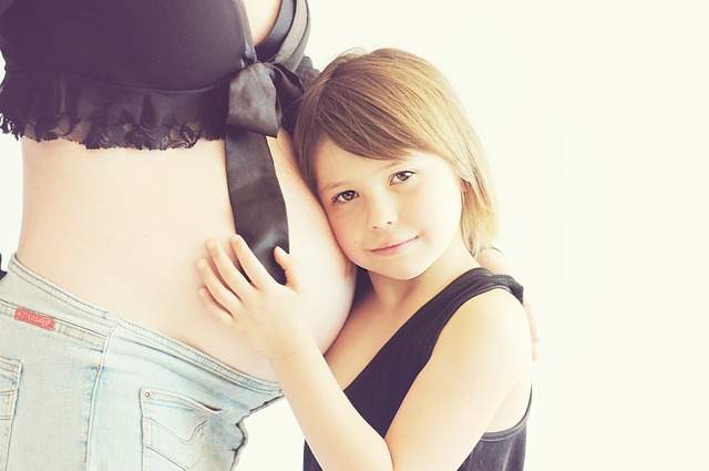 fille qui écoute le ventre d'une femme enceinte