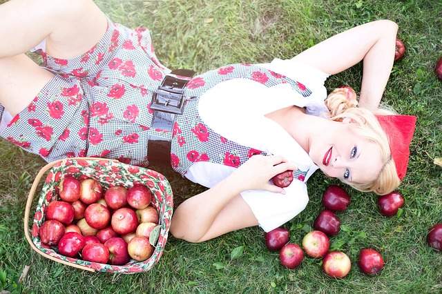 femme souriante avec des pommes rouges bio