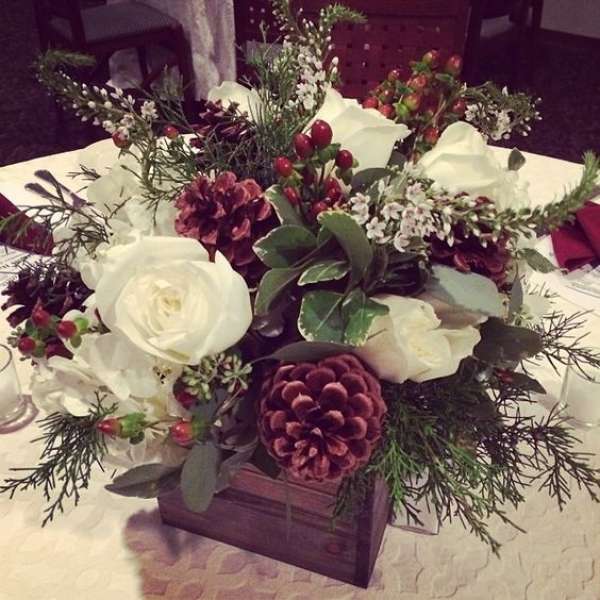 Centre de table avec des roses blanches et des pommes de pin