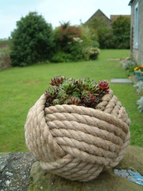 Décoration de jardin avec un pot de fleur caché par une boule de corde