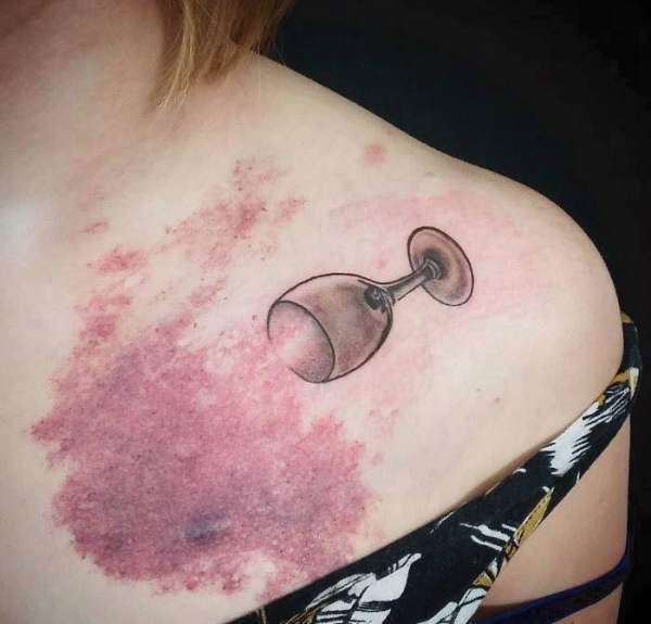 Un tatouage verre de vin rouge renversé pour embellir cette tache de naissance