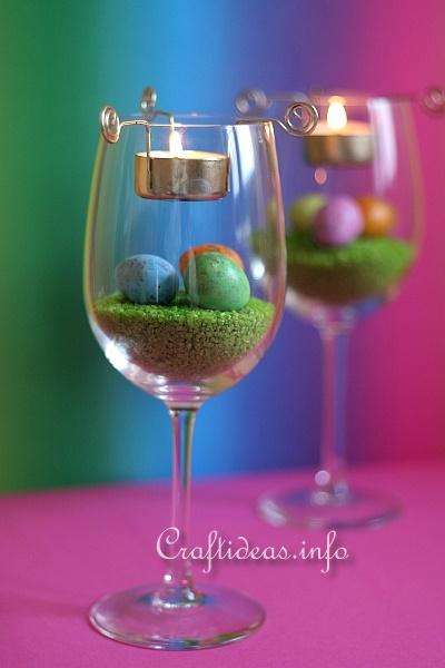 Verres à vin avec du sable coloré et de faux œufs qui feront un joli centre de table pour la décoration de Pâques