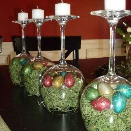 Décoration de table pour Pâques avec de grands verres à pied transformés en nids avec du papier déchiqueté et de faux œufs
