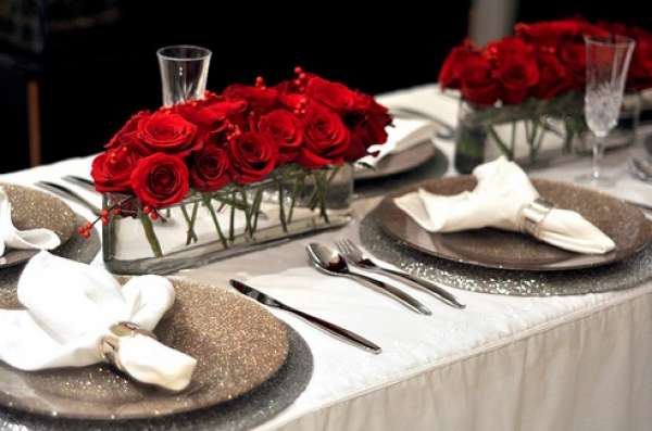 Des roses rouges et des assiettes à paillettes pour une décoration de Noël raffinée