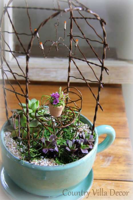 Una tazza da tè con un giardino succulento e finto ferro battuto