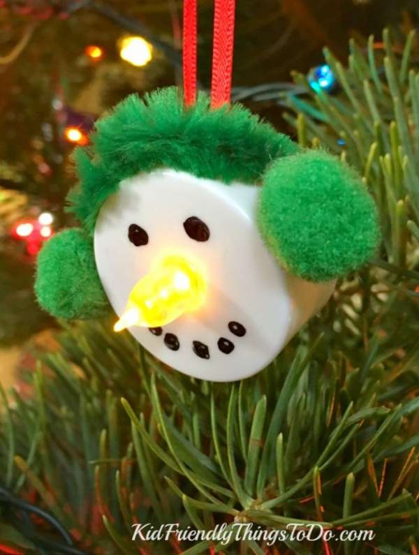 Un bonhomme de neige avec une bougie LED, un marqueur et des Pom-Poms