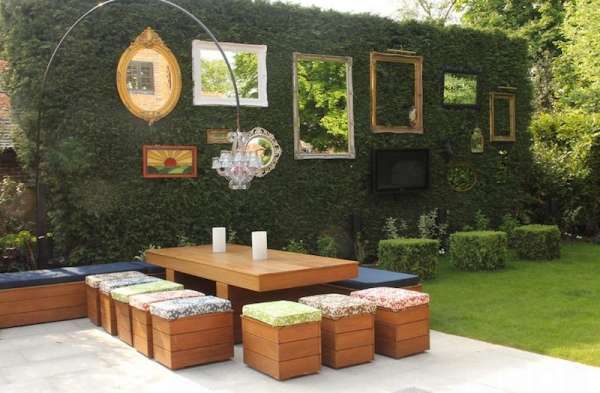Jardin moderne avec coin repas extérieur et mur végétal décoré de cadres design