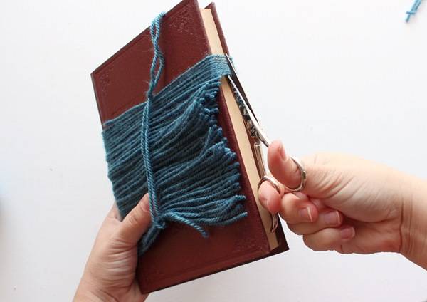 découper le fil de laine enroulé autour du livre pour faire une crinière de tête de cheval à chevaucher