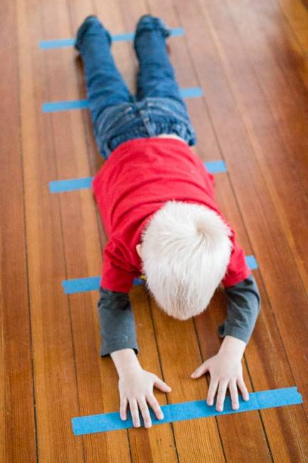 enfant qui s'étire par terre pour mesurer sa taille