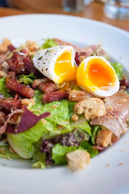 Oeuf à la coque 4 minutes coupé en deux sur une salade composée