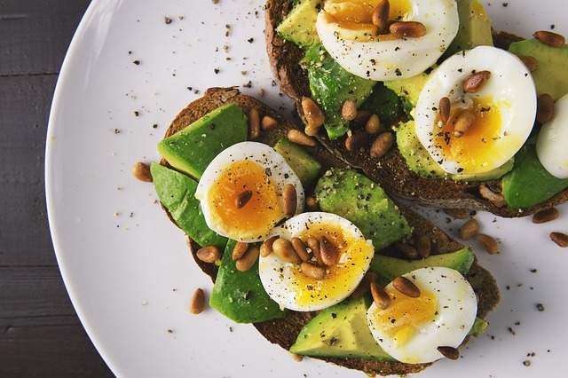 œufs mollets coupés sur des tartines de pain avec des tranches d'avocat