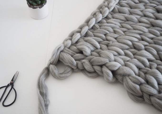 finition et dernière étape de la fabrication d'une couverture tricotée avec les bras