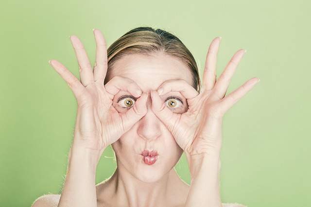 femme qui met ses doigts devant les yeux comme des lunettes