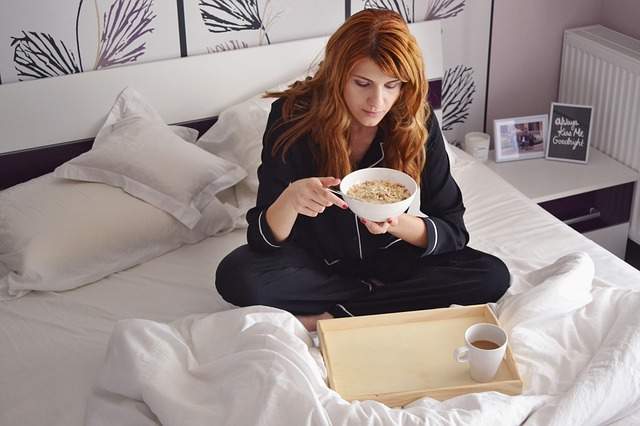 femme qui prend son petit déjeuner au lit