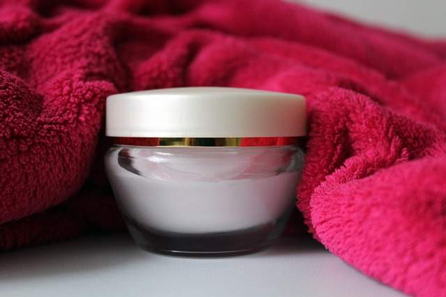 pot de crème pour le visage et serviette éponge