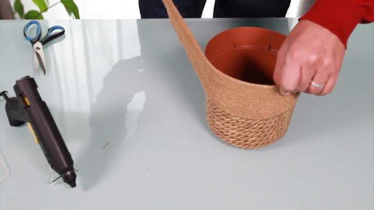 collage du ruban en toile de jute pour décorer le pot de fleur en plastique