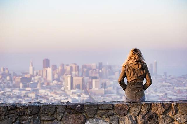 femme seule entrain de regarder une ville à l'horizon