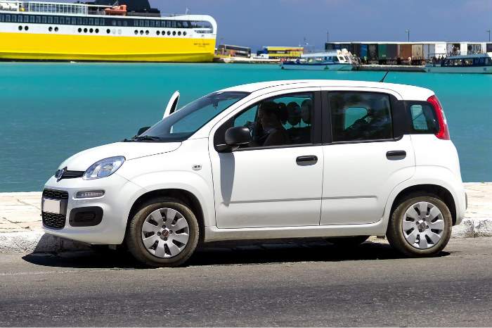 voiture garée au soleil sur un quai au bord de la mer