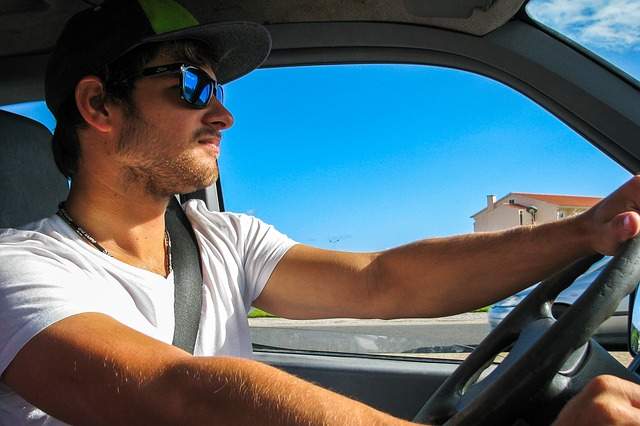 homme au volant d'une voiture par une journée ensoleillée