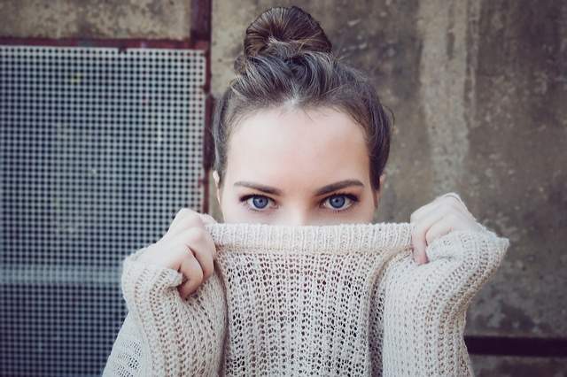 jeune femme qui se cache derrière son pull