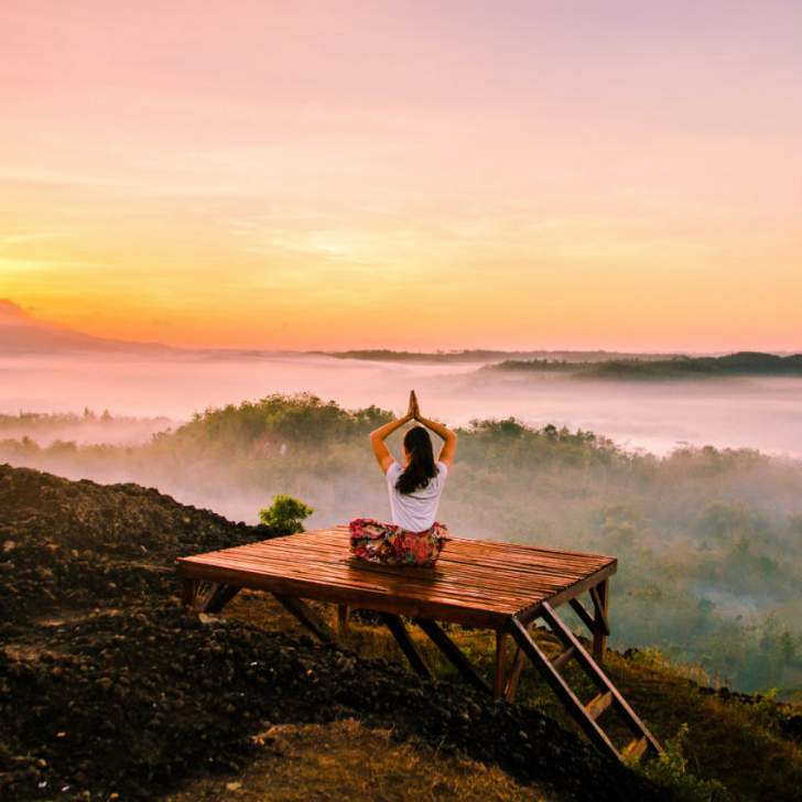 fille qui fait du yoga sur une estrade à la montagne