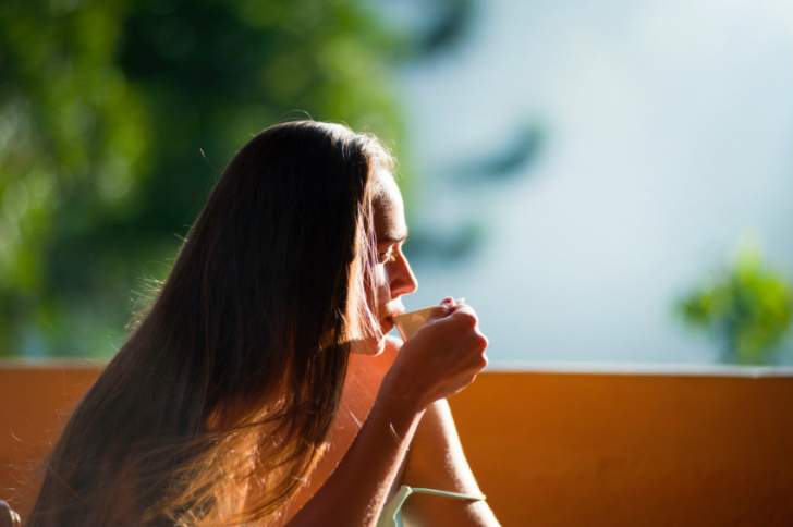 fille assise au soleil qui boit une tasse de thé