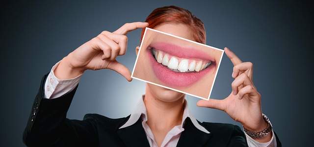 femme tenant une photo de bouche souriante avec des dents et des gencives saines