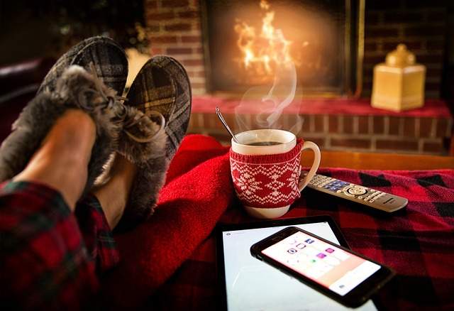 Au chaut à la maison en hiver devant la cheminée avec une boisson chaude