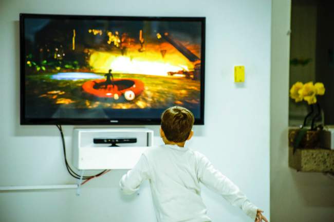 Enfant qui joue à la console sur la télé dans le salon