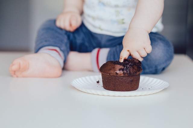 bébé qui met le doigt dans un muffin au chocolat